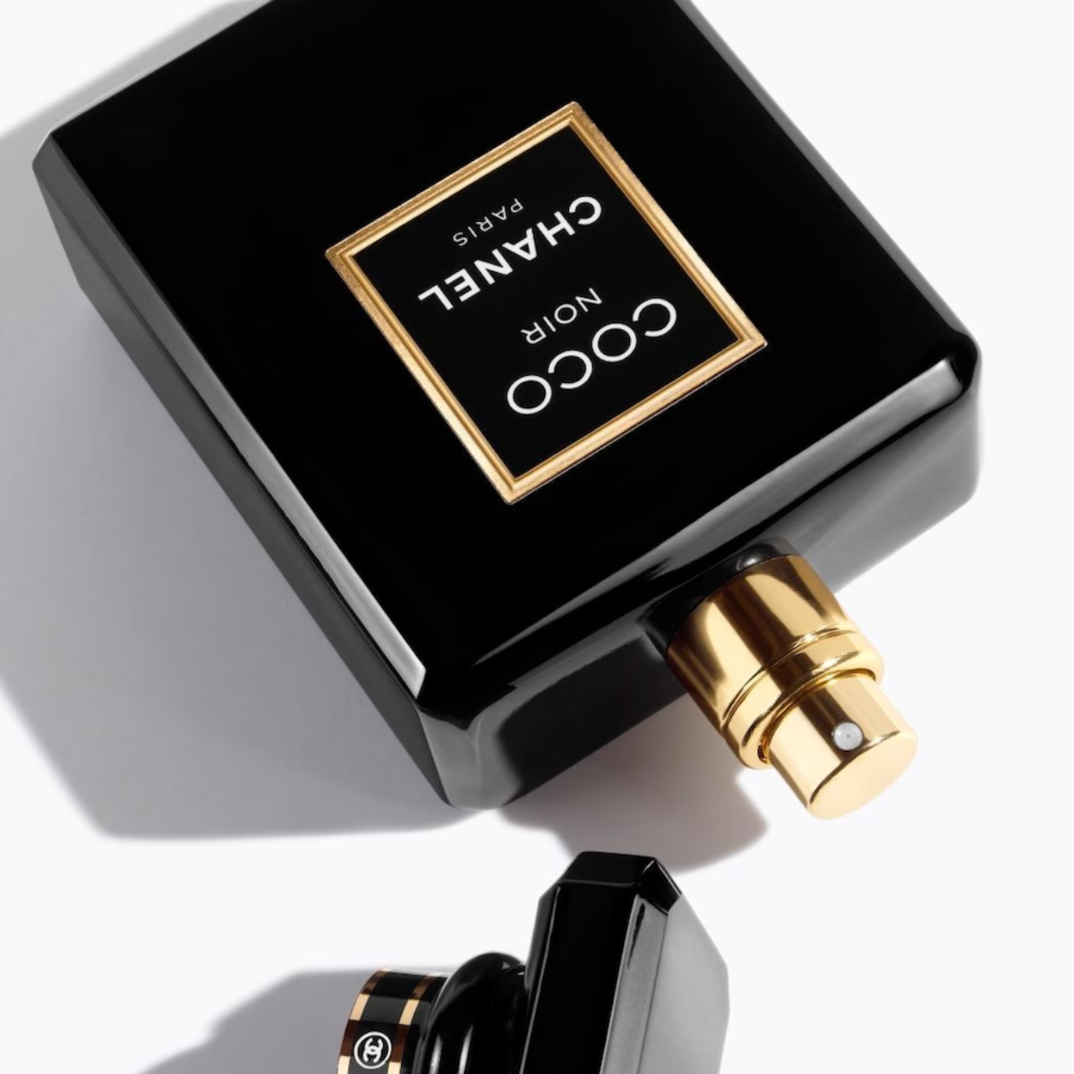 Black Chanel perfume bottle with gold cap on a white background