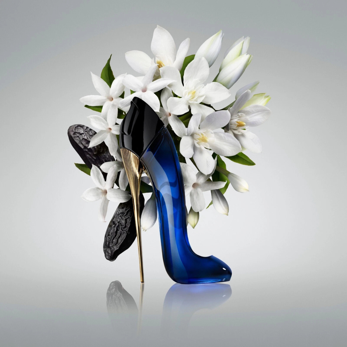 Blue high-heeled shoe with gold heel on a gray background with white flowers