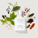 Creed Silver Mountain Water perfume bottle surrounded by natural elements on a light background
