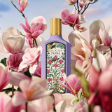 Gucci Flora perfume bottle surrounded by pink flowers with a blue sky background