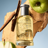 Hugo Boss bottle with apples and cinnamon on a wooden surface