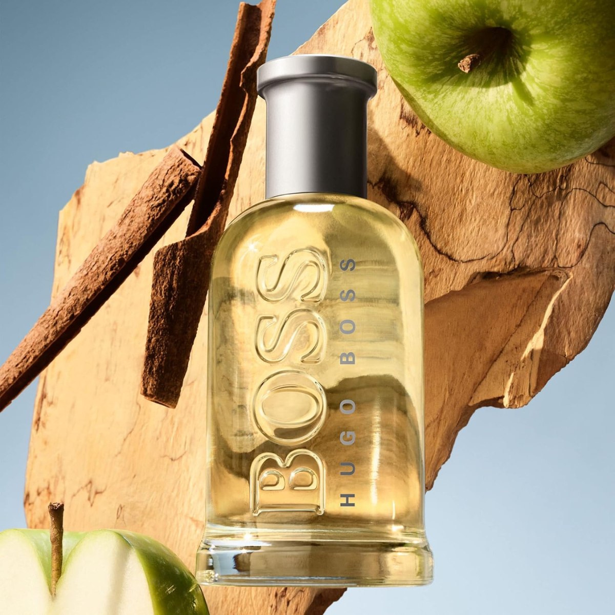 Hugo Boss bottle with apples and cinnamon on a wooden surface