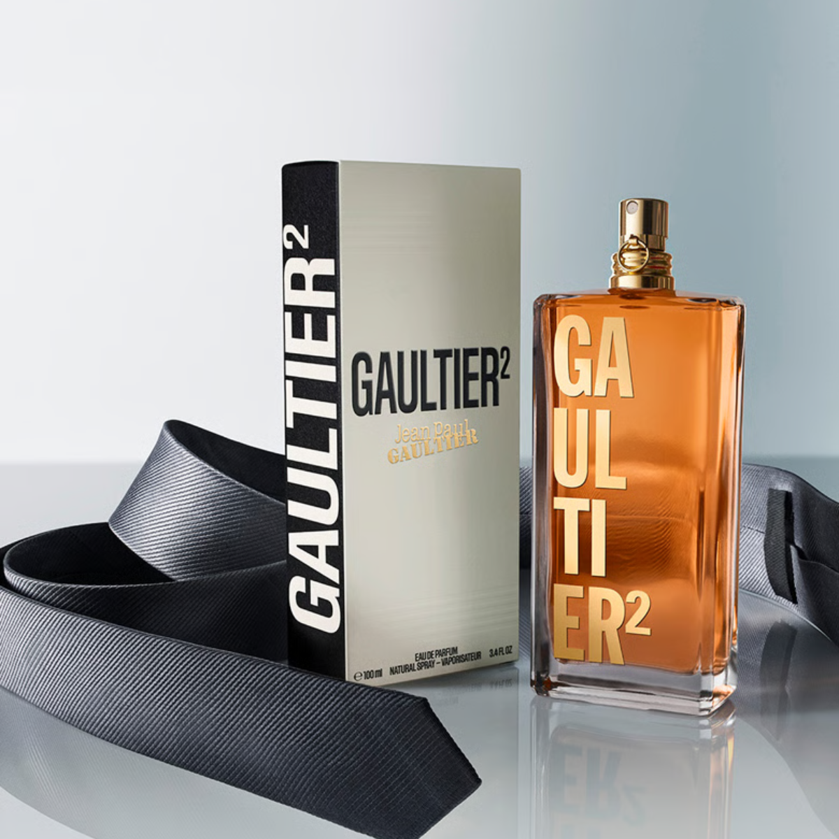 Gaultier 2 perfume bottle and packaging with a tie on a reflective surface