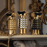 Three decorative bottles with gold and black designs on a reflective surface.