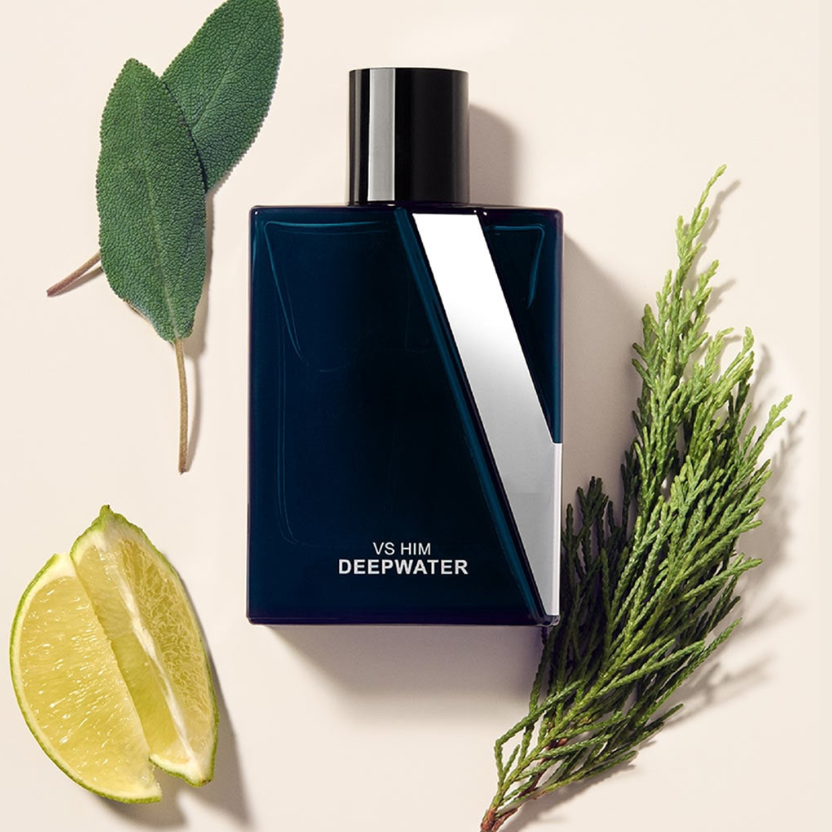 Blue perfume bottle labeled 'VS HIM DEEPWATER' with green leaves and a lime wedge on a beige background