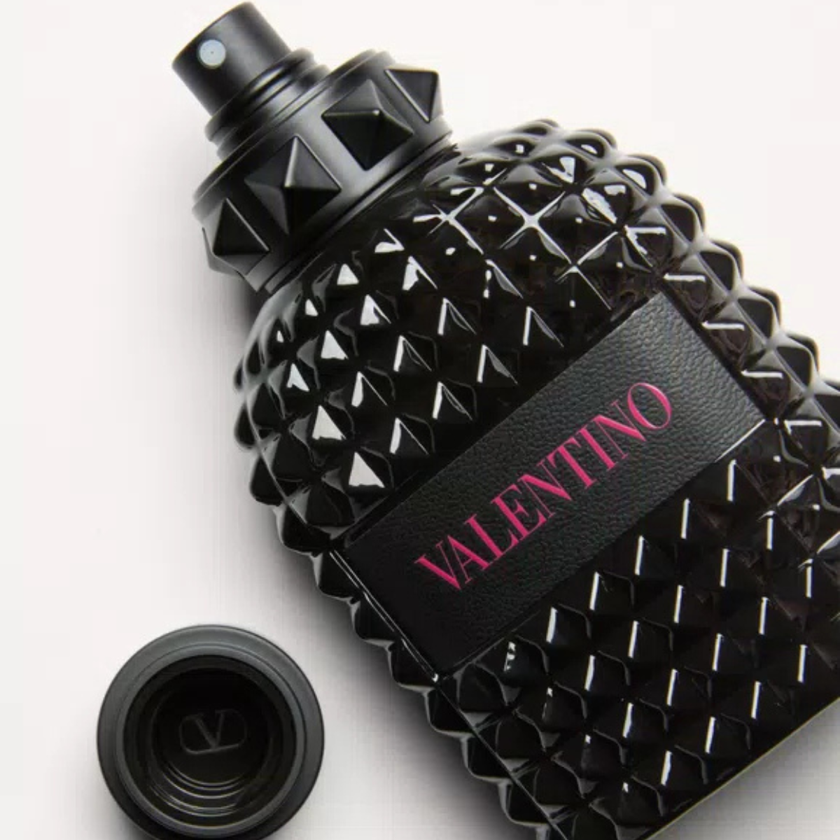 Black studded perfume bottle with 'Valentino' branding on a light gray background