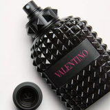 Black studded perfume bottle with 'Valentino' branding on a light gray background