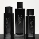 Three black YSL perfume bottles of different sizes on a reflective surface with a white background.